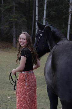 a girl standing next to a black horse