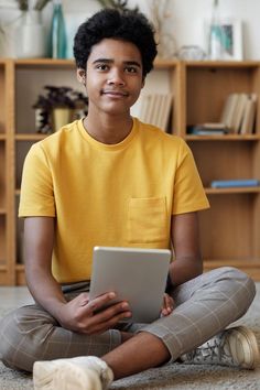 a young man sitting on the floor using a tablet