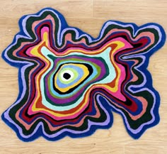 a multicolored area rug with an eye in the center on a wooden floor