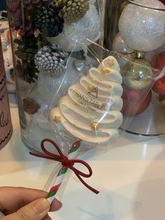 a hand holding a candy cane with christmas decorations in the background