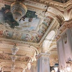 an ornate ceiling with paintings and chandeliers in a room that is painted white