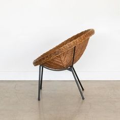 a wicker chair sitting on top of a cement floor next to a white wall