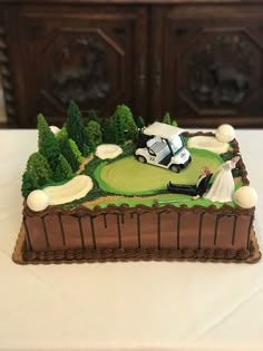 a golf themed cake on a table with white linens and brown wood cabinets in the background