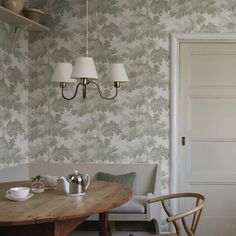 a dining room table with two lamps hanging from the ceiling