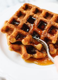 a waffle on a white plate with syrup being drizzled over it