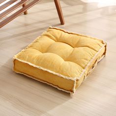 a yellow square dog bed sitting on top of a hard wood floor next to a wooden bench