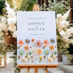 an easel with flowers and greenery in front of a sign that reads, welcome to the wedding of sophiie and olliver