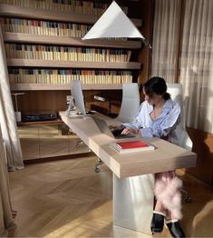 a woman sitting at a desk in front of a book shelf