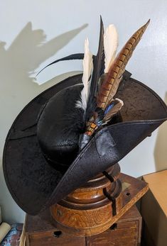 Musketeer Hat - one side down for the firing yer musket or waving yer sword..  Stylish Classic and effective. ~ Hand made feather set secured to the brim and crown.  1 x Long tail Pheasant feather with Swan and crow  feathers  Green sheen Rooster feathers . Brixham pirate style, Party, festival fun and Adventure. External Leather hat band - hand stitched. This will taek you to another dimension.  Sharp, stylish and flamboyant. This is a durable, long lasting period hat. Distressed leather look w Musketeer Hat, Feathered Hat, Crow Feather, Pirate Fashion, Pirate Hat, Rooster Feathers, Pheasant Feathers, Pirate Hats, Feather Hat