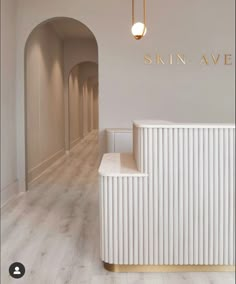 the entrance to skin ave is lined with white walls and wood flooring, along with an arched doorway