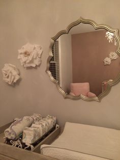 a mirror hanging on the wall next to a dresser with diapers in front of it