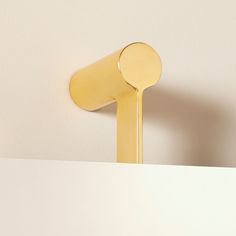 a close up of a gold spoon on top of a white surface with a wall in the background