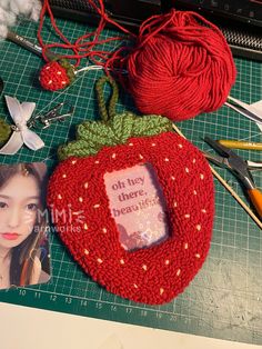 there is a red strawberry on the table next to some scissors and knitting needless