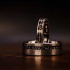 two wedding rings are sitting on top of each other in front of a dark background