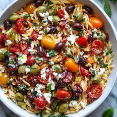 a bowl filled with pasta, olives, tomatoes and feta cheese on top