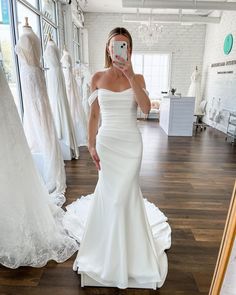 a woman is taking a selfie in front of her wedding dress on the floor