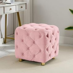 a pink tufted ottoman sits in front of a white desk and plant on the floor