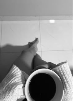 a person laying on the floor holding a cup of coffee