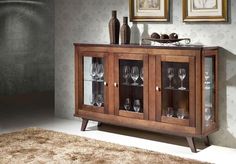 a wooden cabinet with glass doors and wine glasses on it's front shelf in a living room