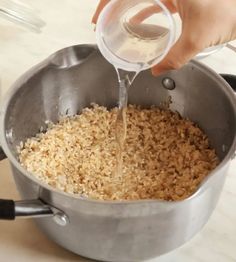 someone pouring water into a pot filled with rice