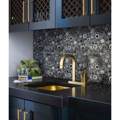 a kitchen with black cabinets and gold faucets on the countertop, next to a sink