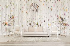 a living room with floral wallpaper and white furniture in front of a curtained wall