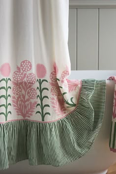 a white toilet sitting next to a bath tub covered in pink and green flowers on it's side