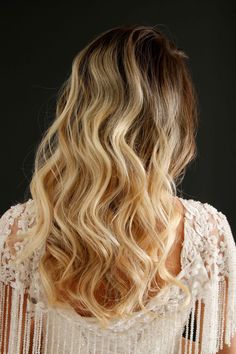 the back of a woman's head with long, wavy blonde hair and fringes