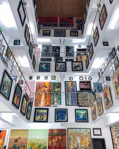 a room filled with lots of framed pictures on the wall next to a ceiling covered in paintings