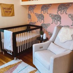 a baby's room decorated in pink, white and black with leopard wallpaper