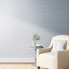 a white chair sitting in front of a wall with a plant on top of it