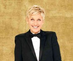 a woman in a tuxedo and bow tie smiling at the camera with her arms crossed