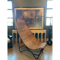 a wicker chaise lounge chair in front of a painting