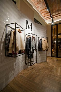 a clothing store with clothes hanging on the wall and wood flooring in front of it