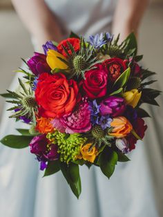 a bride holding a colorful bouquet of flowers