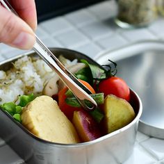 a person is cutting into a salad in a tin with chopsticks on it