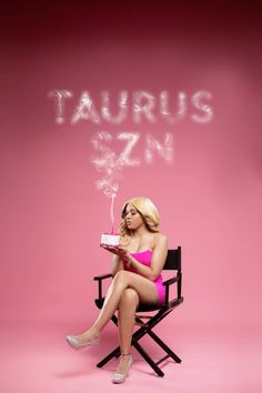 a woman sitting in a chair holding a cake with the word taurus on it