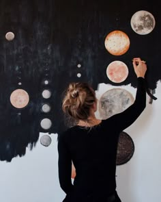 a woman is painting planets on the wall