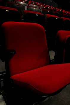 an empty auditorium with red seats and no one in the room to sit down or stand up