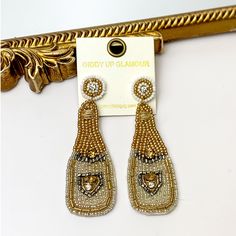 Glam up your look with these delicate Champagne Beaded Earrings! These champagne bottles dangle gracefully with white, gold, and silver beads, adding a unique touch of sparkle and sophistication to your ensemble. Elevate your style today! These earrings are 3.5 inches long. SKU: 0916-2144 Giddy Up Glamour, Champagne Bottles, Gold And Silver, Silver Beads, Beaded Earrings, Sale Items, Champagne, Sparkle, White Gold