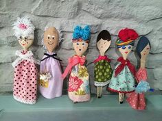 five dolls are lined up against a stone wall