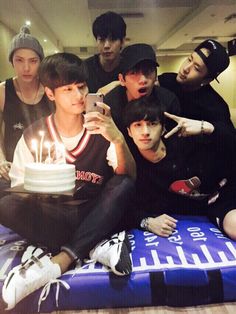 a group of young men sitting next to each other in front of a birthday cake