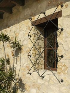 an open window on the side of a stone building with palm trees in front of it