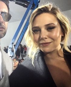 a man standing next to a woman in front of a crowd at a fashion show