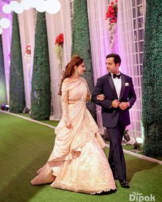 a man and woman in formal wear walking down the aisle at a wedding ceremony with green carpet