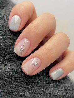 a mani with white and silver designs on the tip of it, sitting next to a gray sweater