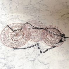 three circular metal objects on a white marble counter top with chains around the edges and links attached to them