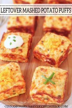 four square pieces of food sitting on top of a wooden cutting board with cheese and sour cream