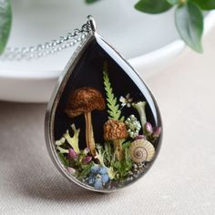 a necklace with an image of mushrooms and other plants in the shape of a tear