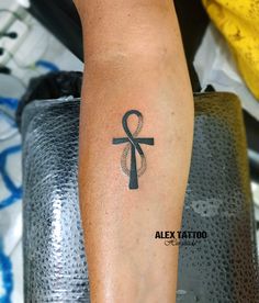 a person with a tattoo on their arm that has an image of an egyptian cross